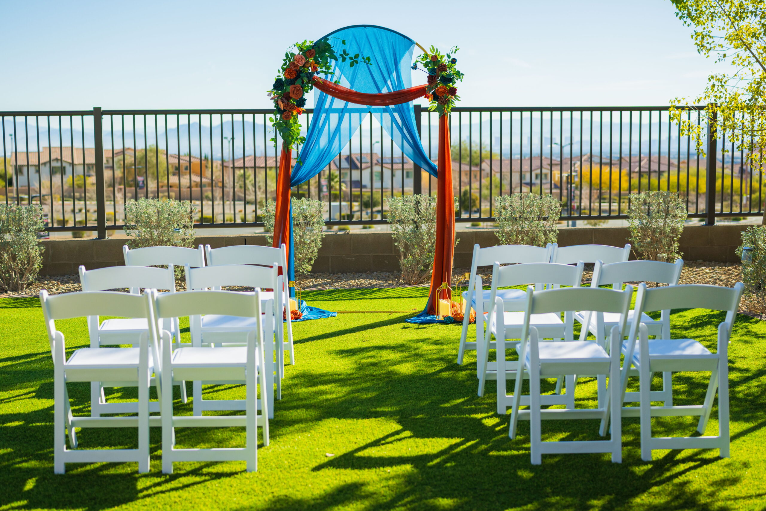 Outdoor wedding ceremony setting with floral arch and white chairs